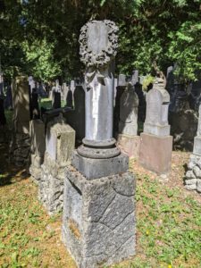 Bild zeigt ein Kindergrab auf dem Alten Jüdischen Friedhof in München: Die abgebrochene Stele ist ein Symbol für das "abgebrochene Leben"